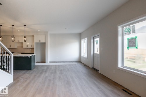 Open-concept living area with wood-finish flooring, recessed lighting, and large windows - 2358 Muckleplum Way Sw, Edmonton, AB 