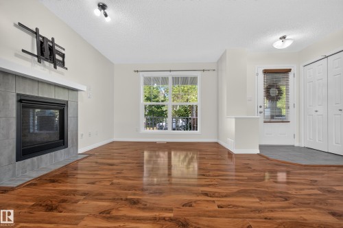 Wood-finish flooring throughout, tiled fireplace with mantel, white trim, and a white paneled door - 6933 21A Avenue Sw, Edmonton, AB 