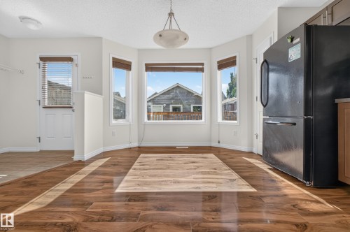 Bay window with multiple panes, wood-finish flooring, white trim, recessed lighting, and a white paneled door - 6933 21A Avenue Sw, Edmonton, AB 