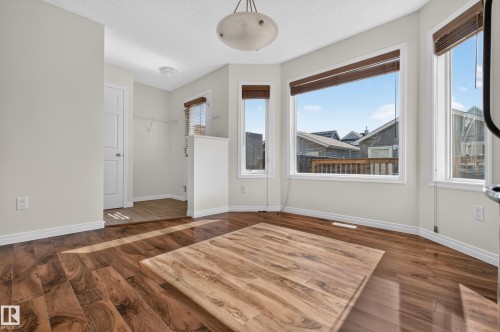 Bay window with multiple panes, wood-finish flooring, white trim, and a semi-flush mount ceiling fixture - 6933 21A Avenue Sw, Edmonton, AB 