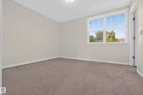 Neutral-toned wall finish, expansive window, white window trim, matching white baseboards, and carpeted flooring - 6933 21A Avenue Sw, Edmonton, AB 