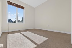 Bright room featuring a large window with brown wood blinds and neutral carpeting - 