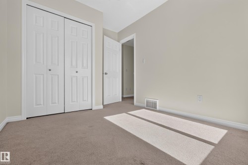 Neutral paint palette with carpeting, white trim, and bi-fold closet doors - 6933 21A Avenue Sw, Edmonton, AB 