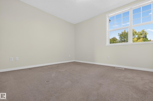 Carpeted room featuring a large multi-pane window and neutral wall tones - 6933 21A Avenue Sw, Edmonton, AB 