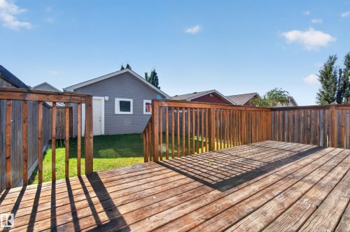 Expansive wooden deck with railing, leading to a manicured lawn - 6933 21A Avenue Sw, Edmonton, AB 
