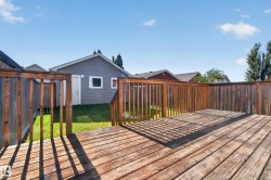 Expansive wooden deck with railing, leading to a manicured lawn - 