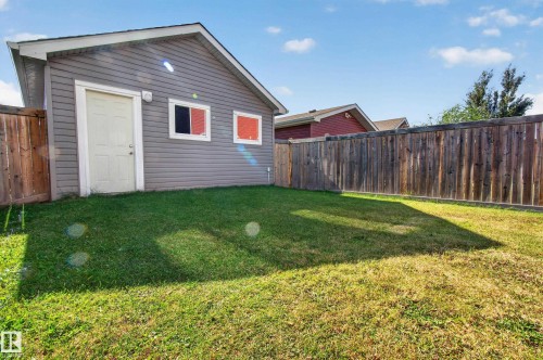 Rear detached structure with gray siding, a white service door, and two windows - 6933 21A Avenue Sw, Edmonton, AB 
