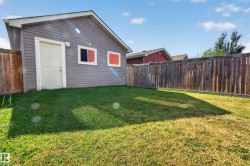 Rear detached structure with gray siding, a white service door, and two windows - 