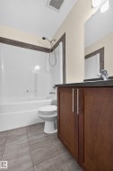 Wood-finish vanity with dual doors and brushed nickel pulls, dark countertop, and undermount sink - 