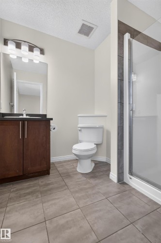 Dark wood-finish vanity with a dark countertop and undermount sink - 6933 21A Avenue Sw, Edmonton, AB 