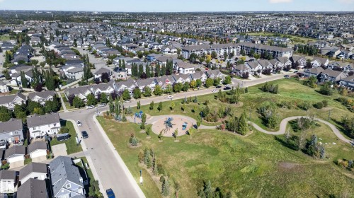 Expansive neighborhood featuring residential properties, a dedicated park area with playground equipment, walking paths, and mature trees - 6933 21A Avenue Sw, Edmonton, AB 