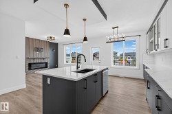 Modern kitchen island with a black sink and faucet, integrated dishwasher, and pendant lighting - 