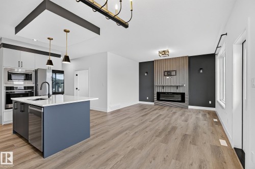 Modern kitchen island with a white countertop and undermount sink - 22 Sydwyck Circle, Spruce Grove, AB 