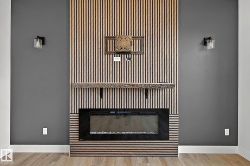 Modern fireplace with a wood-slat feature wall, rustic wood mantel, and integrated sconce lighting - 22 Sydwyck Circle, Spruce Grove, AB 