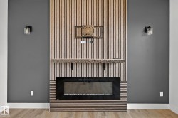 Modern fireplace with a wood-slat feature wall, rustic wood mantel, and integrated sconce lighting - 