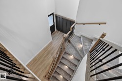 Multi-level staircase featuring carpeted treads with recessed lighting, wood-finish handrails, and black metal balusters - 