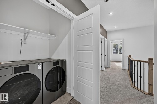 Laundry closet with built-in shelving, front-loading washer and dryer, and panel doors - 22 Sydwyck Circle, Spruce Grove, AB 