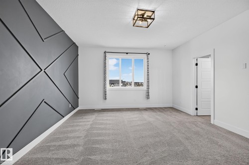Accent wall with geometric paneling, plush gray carpeting, white trim, recessed lighting, and a window with dark curtain rods - 22 Sydwyck Circle, Spruce Grove, AB 
