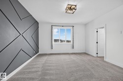 Accent wall with geometric paneling, plush gray carpeting, white trim, recessed lighting, and a window with dark curtain rods - 