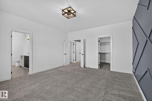 Plush carpeting throughout with a striking accent wall, integrated lighting fixture, and a built-in closet system - 22 Sydwyck Circle, Spruce Grove, AB 