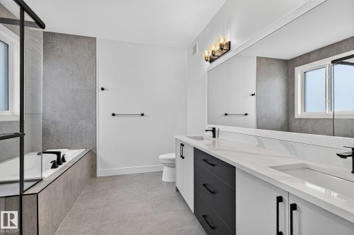 Spacious bathroom featuring a dual vanity with white countertops, integrated sinks, and black fixtures - 22 Sydwyck Circle, Spruce Grove, AB 