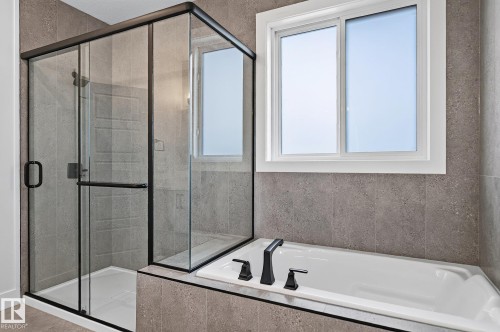 Glass-enclosed shower with matte black hardware, integrated bathtub, and tiled surround - 22 Sydwyck Circle, Spruce Grove, AB 
