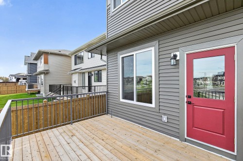 Exterior features a wood deck, gray horizontal siding, and a red entry door with an integrated window - 22 Sydwyck Circle, Spruce Grove, AB 