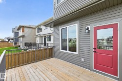 Exterior features a wood deck, gray horizontal siding, and a red entry door with an integrated window - 