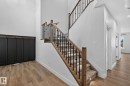 Wood-finish flooring throughout, with a carpeted staircase featuring decorative wrought iron balusters - 22 Sydwyck Circle, Spruce Grove, AB 