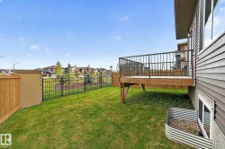 Elevated wood deck with black metal railings, expansive green lawn, wood privacy fence, and black metal perimeter fencing - 