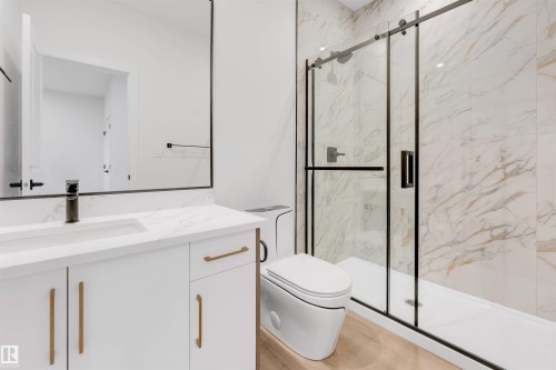 Sleek bathroom featuring a modern vanity with a rectangular undermount sink, a framed mirror, a walk-in shower with a glass enclosure, and large format wall tiling - 13 Trill Point(E), Spruce Grove, AB 