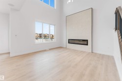 High ceilings with upper transom windows, light wood-finish flooring, and a linear electric fireplace with a tiled surround - 