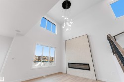 Vaulted ceilings, large windows, a built-in electric fireplace with textured surround, wood-finish flooring, and a modern chandelier - 