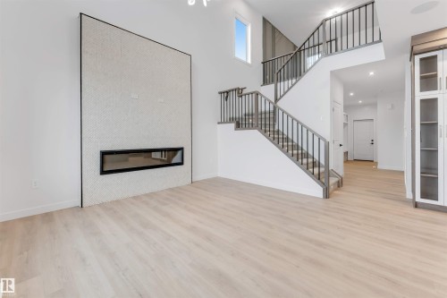Expansive living area featuring soaring ceilings, a linear fireplace set within a full-height tiled accent wall, and light wood-finish flooring - 13 Trill Point(E), Spruce Grove, AB 