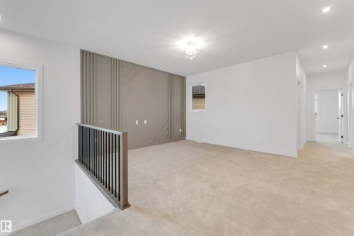 Carpeted room with a decorative accent wall, recessed lighting, and a crystal chandelier - 13 Trill Point(E), Spruce Grove, AB 