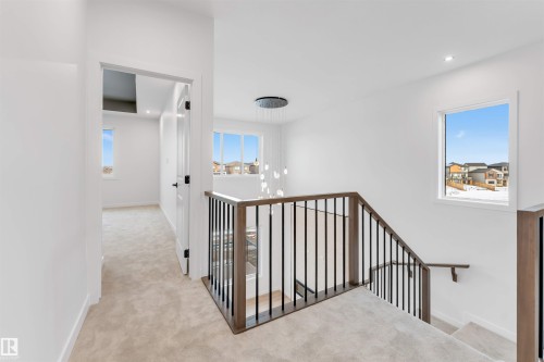 Upper-level hallway with neutral carpeting, white walls, black door hardware, and a contemporary ceiling light fixture - 13 Trill Point(E), Spruce Grove, AB 