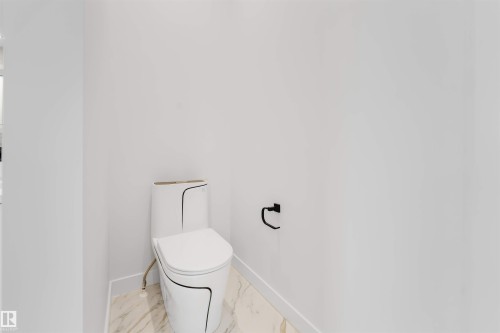 White porcelain toilet with black trim, marble-look flooring, and a matte black toilet paper holder - 13 Trill Point(E), Spruce Grove, AB 