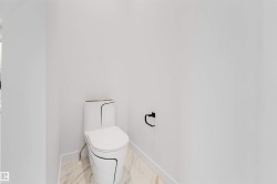 White porcelain toilet with black trim, marble-look flooring, and a matte black toilet paper holder - 