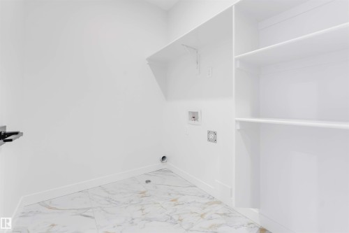 Laundry area with white walls, white trim, white shelving, and marble-patterned flooring - 13 Trill Point(E), Spruce Grove, AB 