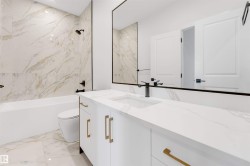 White vanity with gold-tone hardware, rectangular undermount sink, and black wall-mounted faucet - 