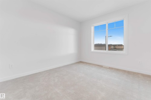 Bright room featuring light gray carpet flooring, white walls, and a large window with white trim - 13 Trill Point(E), Spruce Grove, AB 