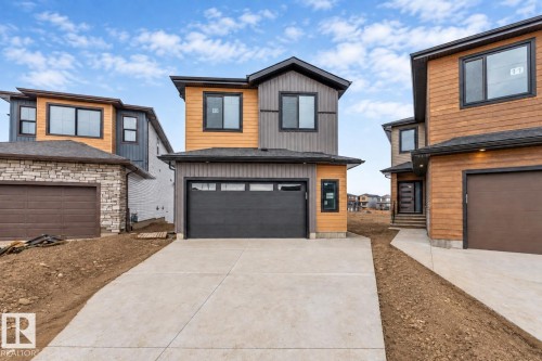 Contemporary exterior with horizontal wood-finish siding, dark trim, and a black garage door - 13 Trill Point(E), Spruce Grove, AB 
