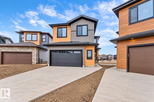 Contemporary exterior design featuring a two-tone facade, dark trim windows, and a dark garage door - 13 Trill Point(E), Spruce Grove, AB 