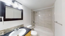 Bathroom featuring a vanity with a dark countertop, white oval sink, and a mosaic tile backsplash - 