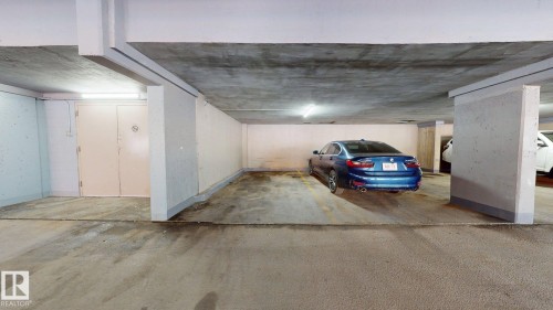 Dedicated parking space within a subterranean garage, featuring concrete flooring and overhead lighting - #307 10140 120 Street Nw, Edmonton, AB - Indoor Photo Showing Garage