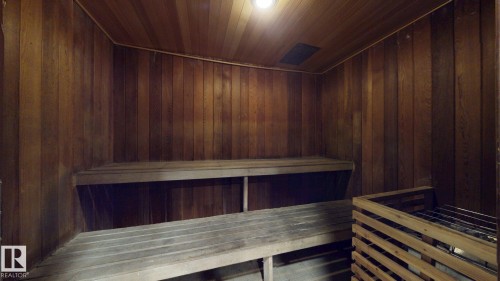 Wood-paneled sauna featuring two tiers of built-in benches, a slatted heater cover, and recessed ceiling lighting - #307 10140 120 Street Nw, Edmonton, AB - Indoor Photo Showing Other Room