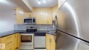 Contemporary kitchen featuring light wood-finish cabinetry, dark countertops, and a mosaic tile backsplash - #307 10140 120 Street Nw, Edmonton, AB  - Indoor Photo Showing Kitchen With Upgraded Kitchen 