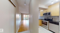 Modern kitchen featuring stainless steel appliances, light wood-finish cabinetry, dark countertops, and a mosaic tile backsplash - 