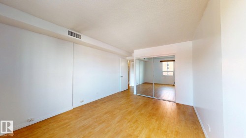 Open interior space featuring wood-finish flooring, white walls, and a textured ceiling - #307 10140 120 Street Nw, Edmonton, AB - Indoor Photo Showing Other Room