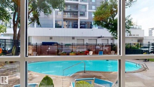 Outdoor swimming pool with integrated steps and metal handrails, surrounded by concrete decking - #307 10140 120 Street Nw, Edmonton, AB - Outdoor With In Ground Pool